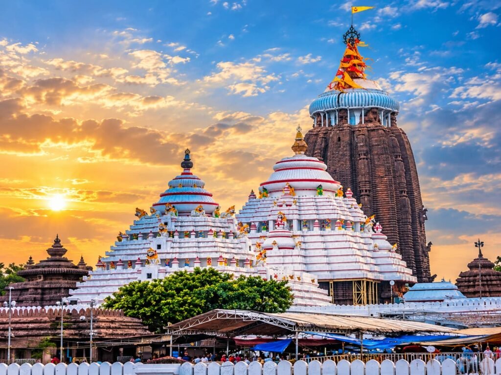 Jagannath Temple in Puri, Odisha, featuring its towering stone shikhara, colorful flags, and intricate temple architecture at sunset